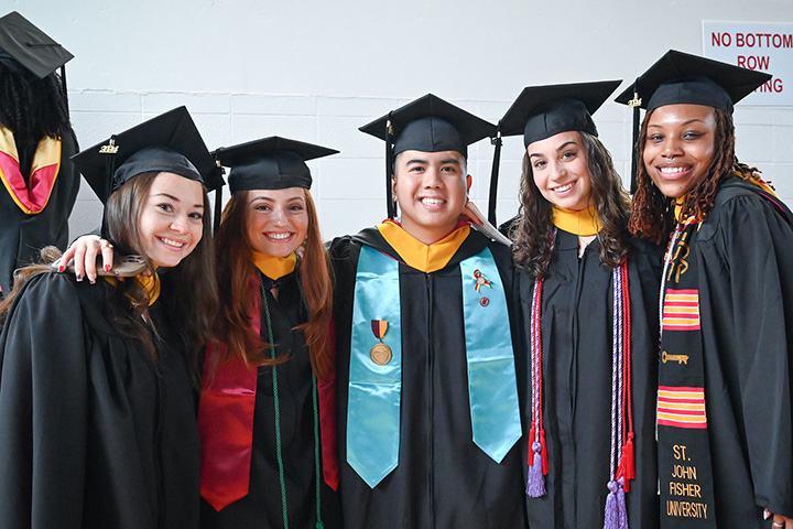 Students smiling together in commencement regalia.