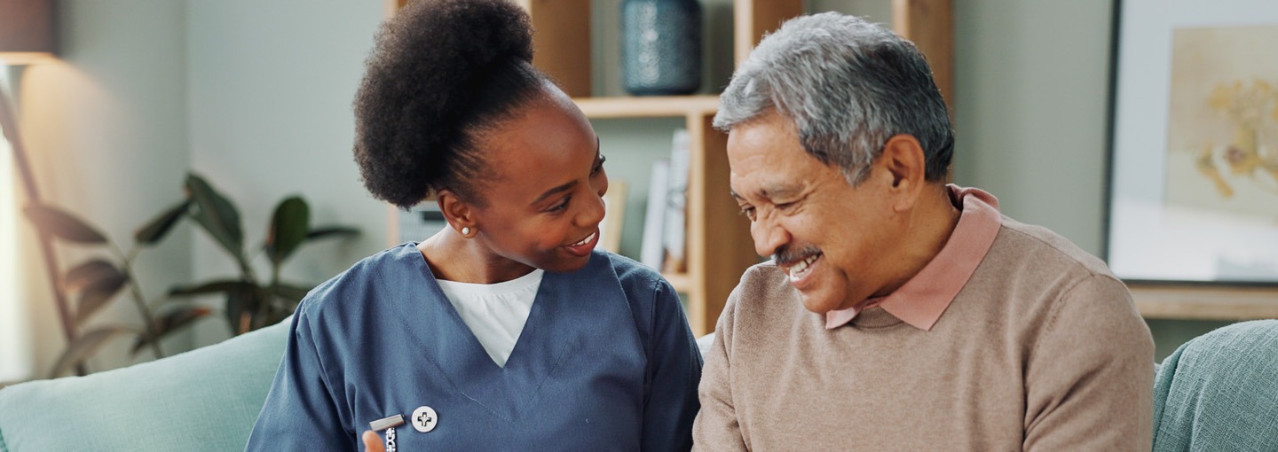 A nurse in scrubs working with a patient in their home.