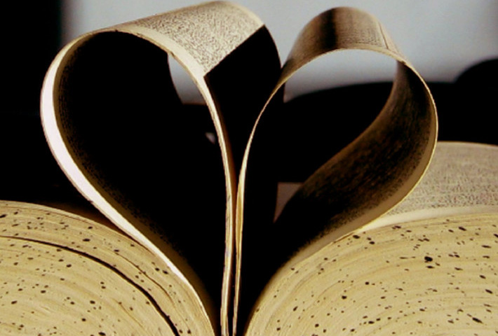 Pages of an open book shaped into a folded heart.