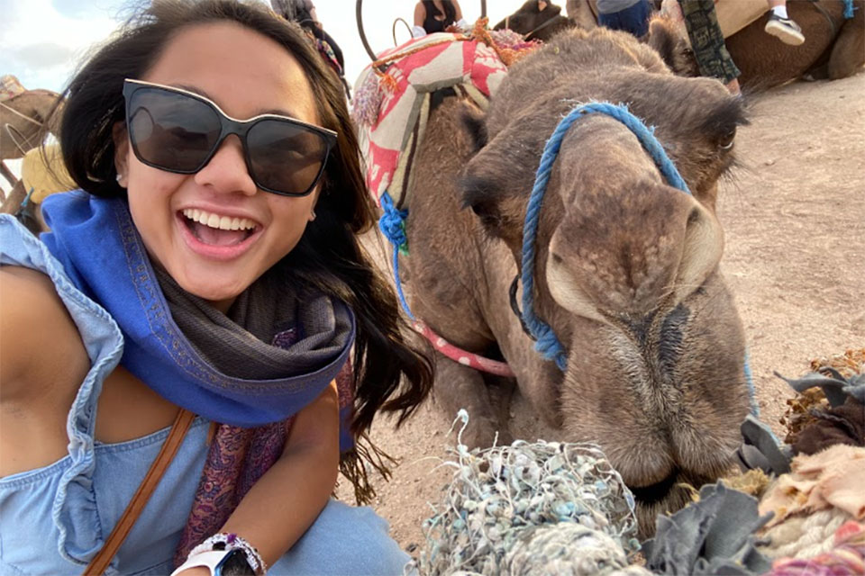 A Fisher student poses with a camel while in Morocco.