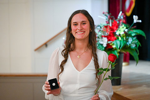 A December graduate of the Wegmans School of Nursing holds up a pin.