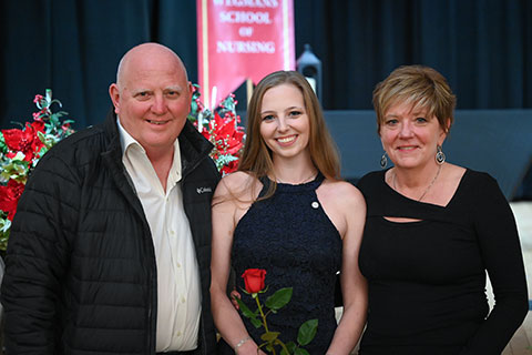 A graduate poses with family members.