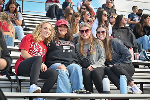 Four Fisher students cheer on the Cardinals from the stands during the Courage Bowl.