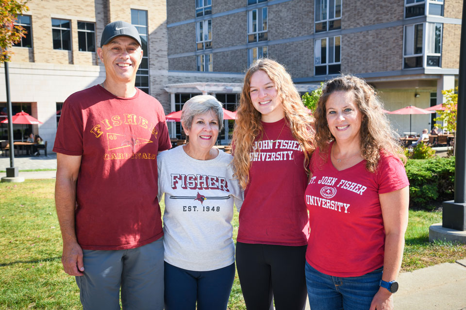 A family all wearing Cardinal gear pose together during Family Weekend.