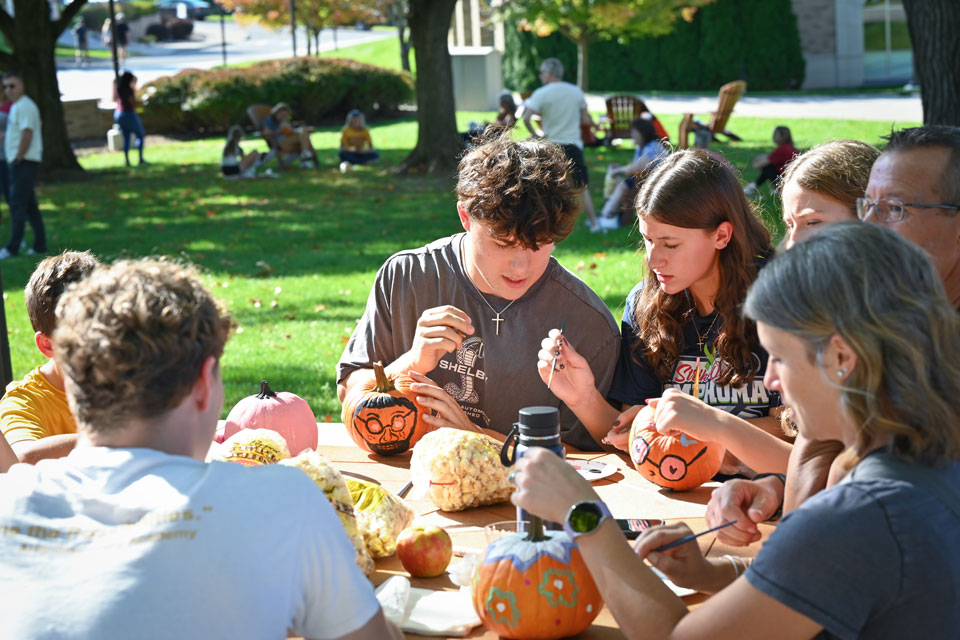 Fisher students and their families paint pumpkins during Family Weekend.