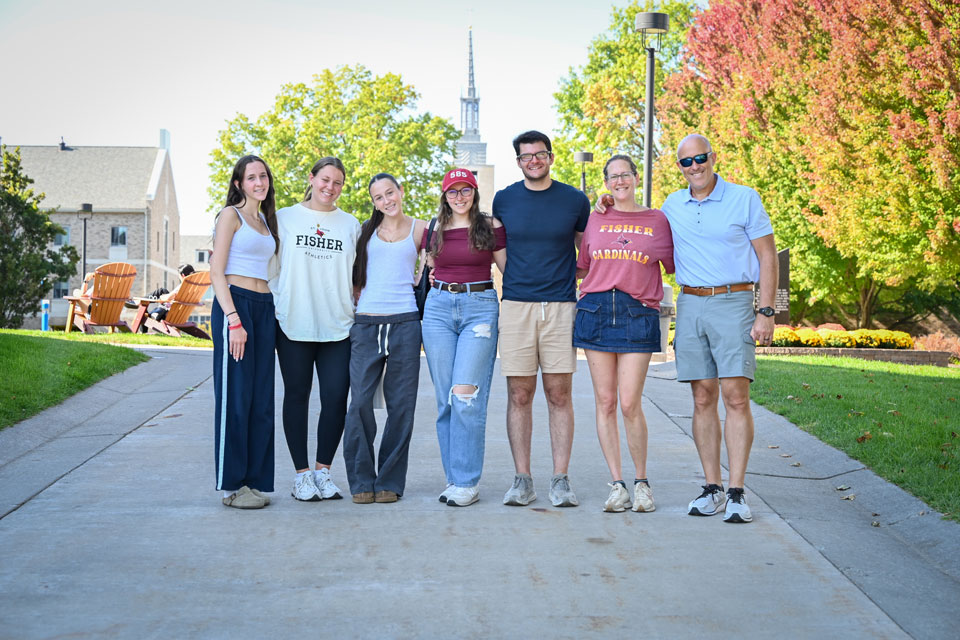 Members of the Fisher community pose with the Kearney Hall Steeple in the background.