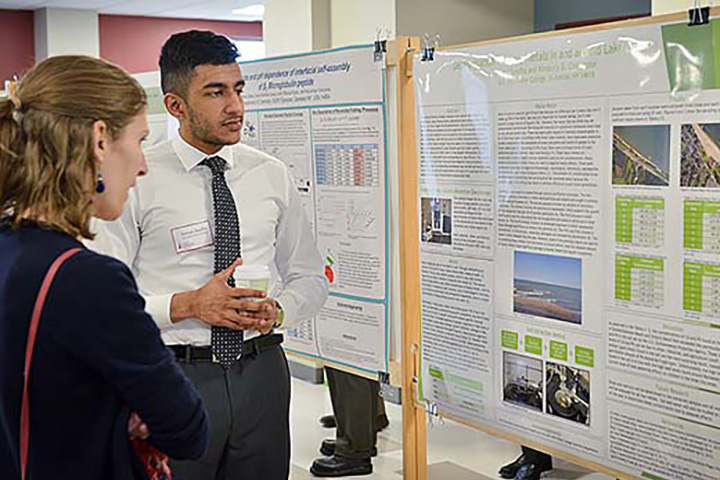 A student shares research on a poster at the Fisher Showcase.