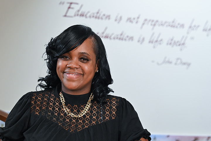 An educator stands confidently in a school hallway.