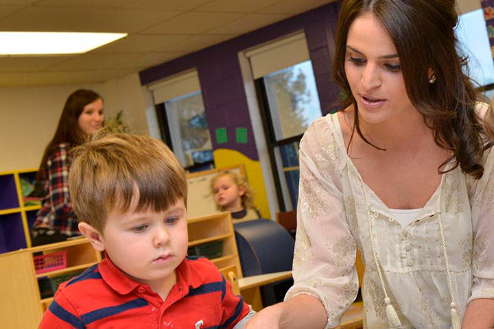 An educator reads to a student in an elementary class.