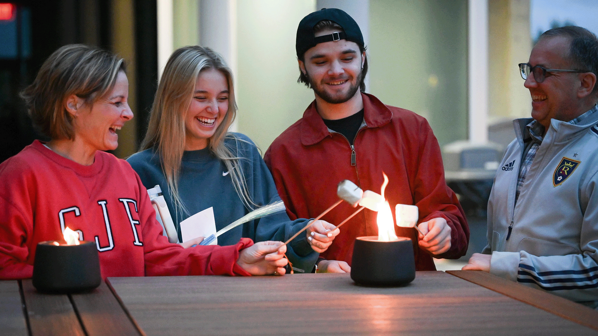 Families roast marshmallows during Fisher Family Weekend.