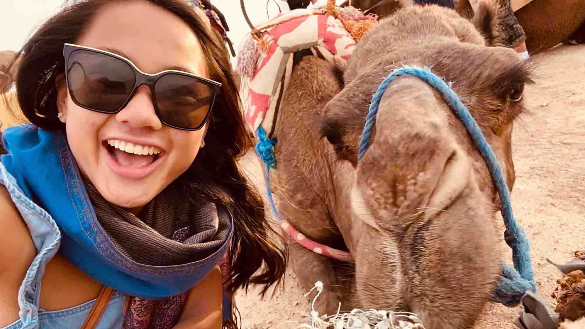 A student smiling with a camel.