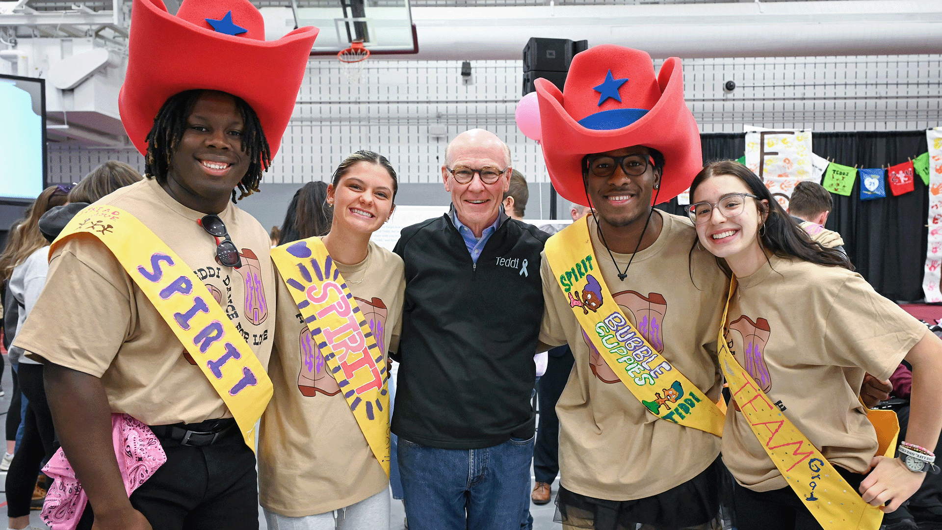 The spirit team for the Teddi Dance for Love stands together with giant red cowboy hats and sashes.