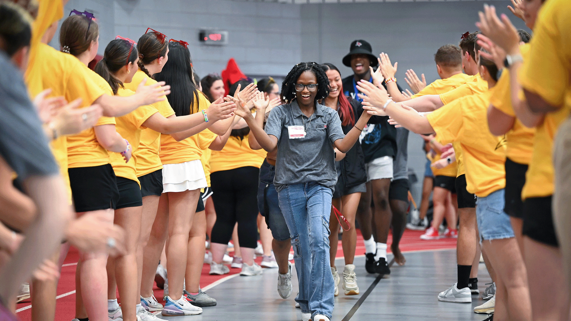 A group of students high-five and welcome <a href=