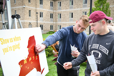 New graduates place a sticker on a map of NY to show where they are going.