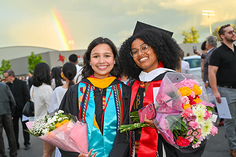 Graduating students celebrate Commencement and a rainbow is in the sky.
