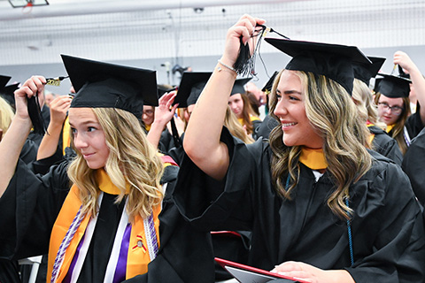 A graduate moves a tassel on her cap at St. John Fisher University's Commencement.
