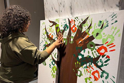 A student add her handprint to a tree mural.