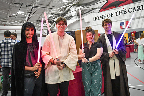 Students holding lightsabers share their research at the Fisher Showcase.