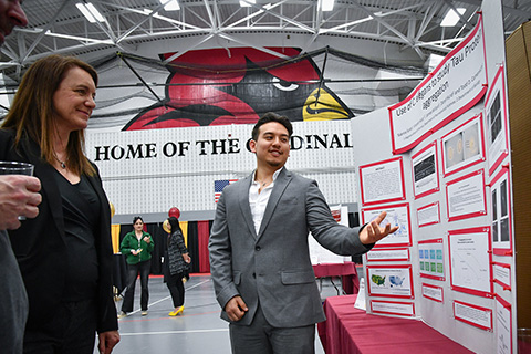 Students and professors discuss student research on display at the Fisher Showcase.