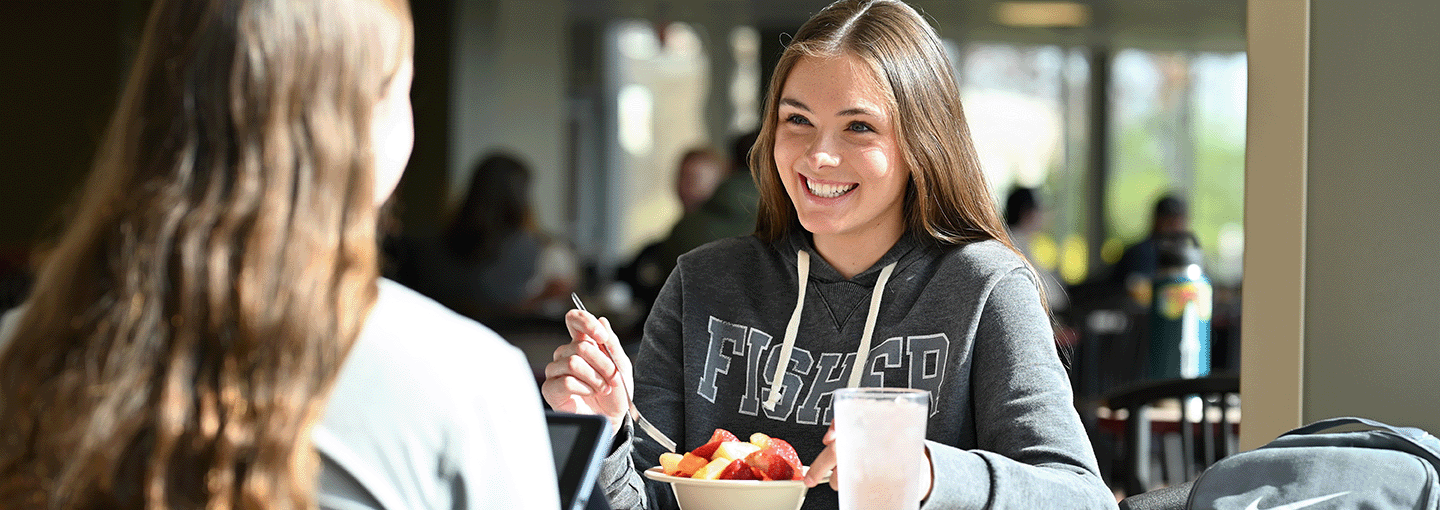 Student eating fruit in the Ward-Haffey Dining Hall at Fisher.