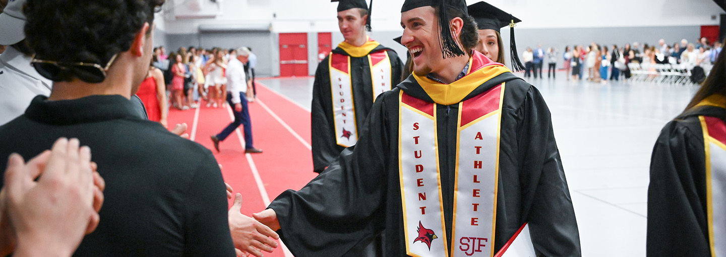 Student athletes celebrate in commencement regalia with sashes to identify Fisher student athletes.