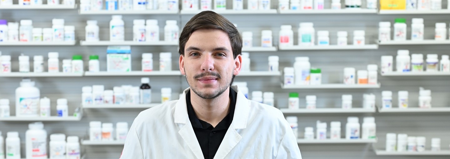 A pharmacy student stands in front of bottles