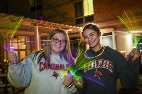 Students wave glow sticks in the evening light on campus.