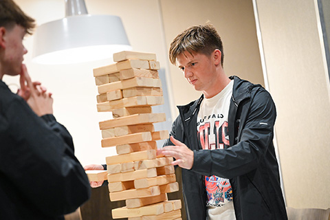 Students play a tower building game with large blocks.