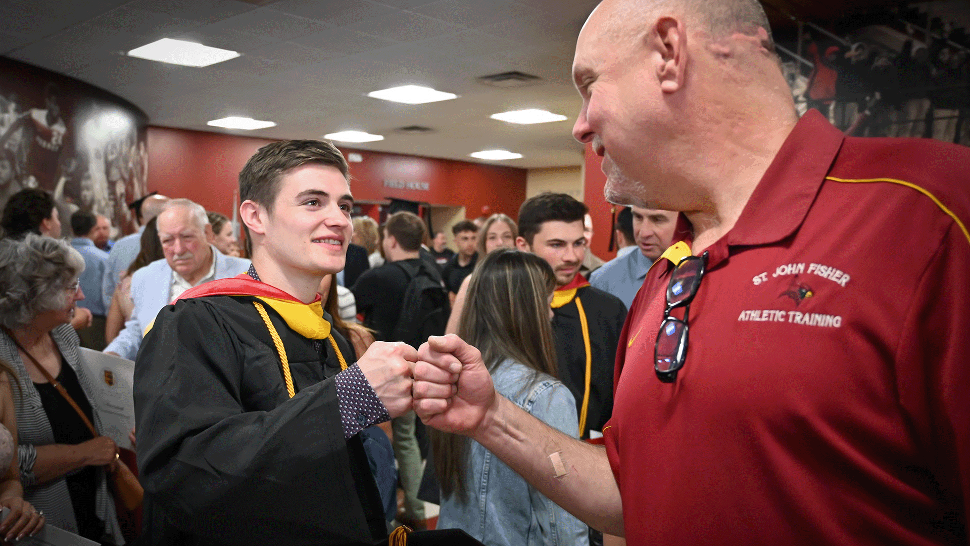 A graduate fist bumps a Fisher athletic trainer.